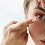 Picture of a young woman placing a contact lens onto her eye